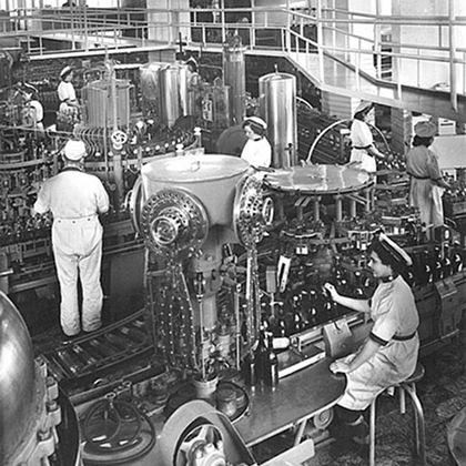 Historic black-and-white photo of workers in the Piedbœuf brewery bottling line, marking the launch of Jupiler Urtyp in 1959.