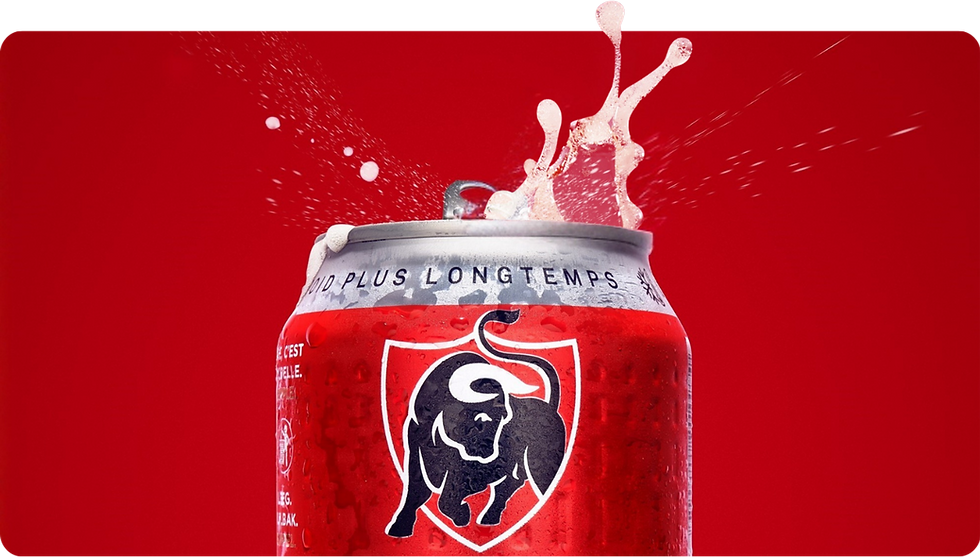 Canette de bière Jupiler avec de la mousse éclaboussante sur fond rouge